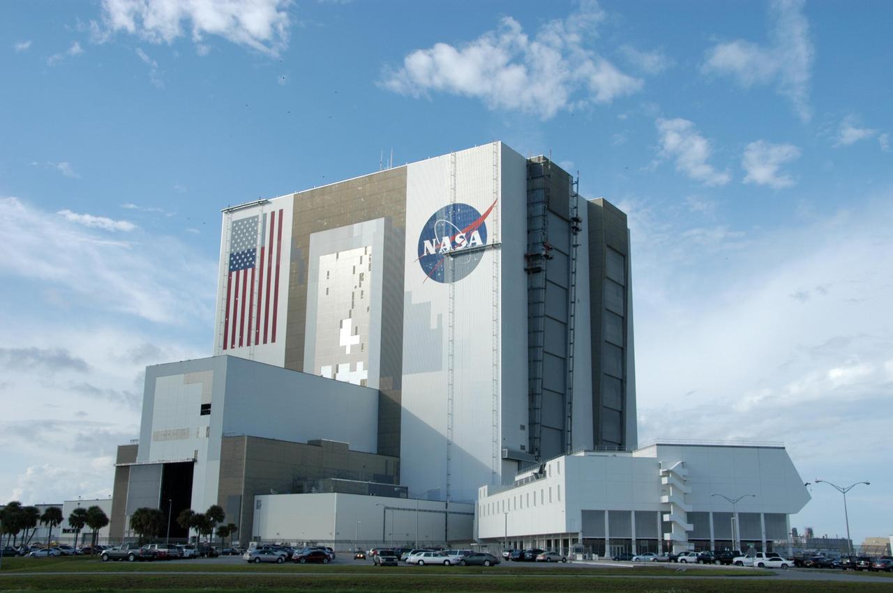 KENNEDY SPACE CENTER, FLA. --   Elevated platforms are seen hanging in front of the NASA Logo on the side of Kennedy Space Center's Vehicle Assembly Building. Also in view on the east side of the building are platforms on the facility's large vertical doors. Workers, suspended on the platforms from the top of the 525-foot-high VAB, use rollers and brushes to do the painting. The flag and logo were last painted in 1998, honoring NASA's 40th anniversary. The flag spans an area 209 feet by 110 feet, or about 23, 437 square feet. Each stripe is 9 feet wide and each star is 6 feet in diameter. The logo, also known as the "meatball," measures 110 feet by 132 feet, or about 12,300 square feet. Photo credit: NASA/George Shelton