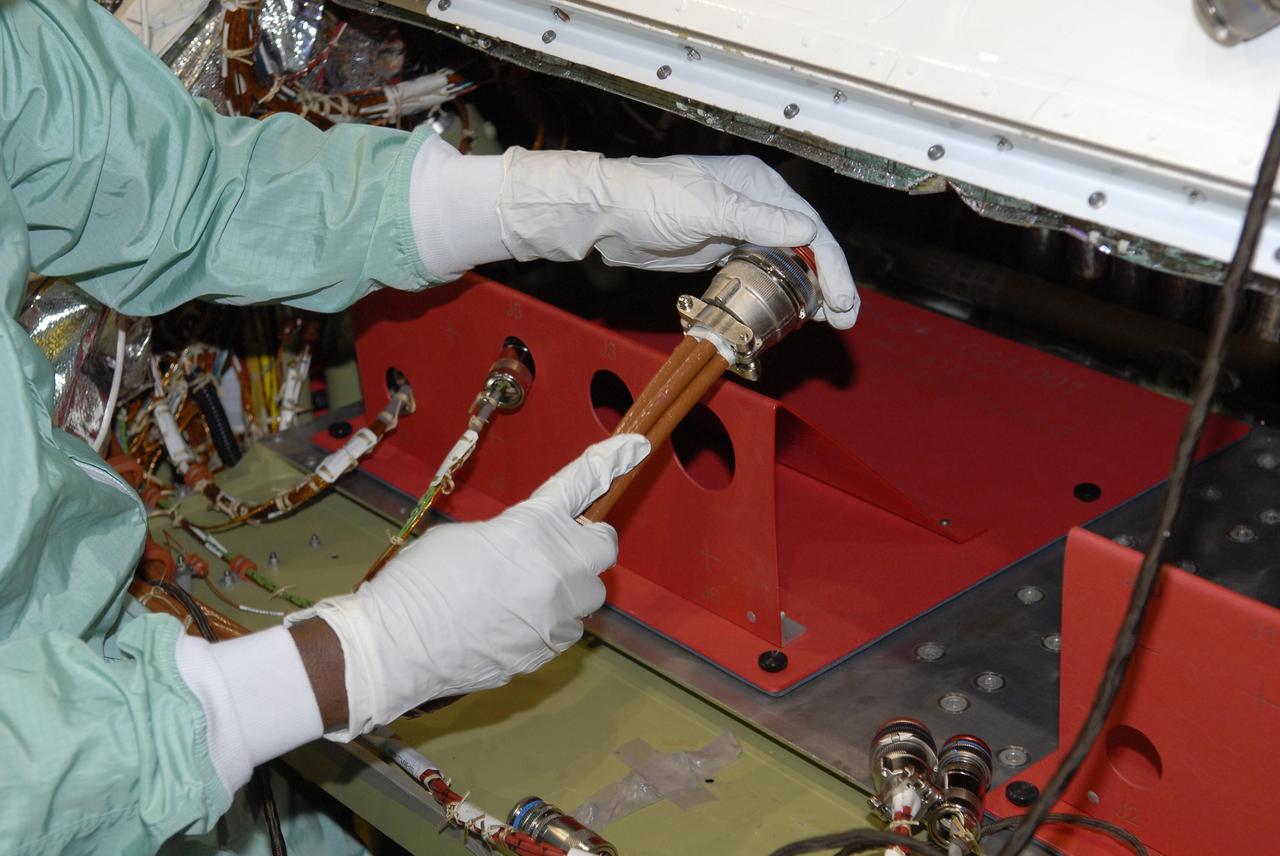 KENNEDY SPACE CENTER, FLA. --  Inside Endeavour's opened payload bay, a worker installs a wiring modification called the "Station to Shuttle Power Transfer System," or SSPTS. The SSPTS allows the space shuttle to stay docked at the International Space Station longer by providing its power and preserving its consumables.  Endeavour is scheduled for mission STS-118 in June.  It will be the orbiter's first shuttle flight in nearly five years. The vehicle has undergone an extensive modification period, including the addition of all of the return-to-flight safety modifications added to both Discovery and Atlantis.  The June mission will deliver another starboard solar array, S5, to the International Space Station.  Photo credit: NASA/Kim Shiflett