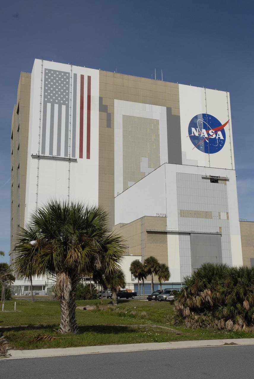 KENNEDY SPACE CENTER, FLA. --  Painters' platforms are seen hanging on the side of Kennedy Space Center's 525-foot-high Vehicle Assembly Building to facilitate the repainting of the American flag and the NASA logo. Workers use rollers and brushes to do the painting. The flag and logo were last painted in 1998, honoring NASA's 40th anniversary. The flag spans an area 209 feet by 110 feet, or about 23,437 square feet. Each stripe is 9 feet wide and each star is 6 feet in diameter. The logo, also known as the "meatball," measures 110 feet by 132 feet, or about 12,300 square feet. Photo credit: NASA/Kim Shiflett