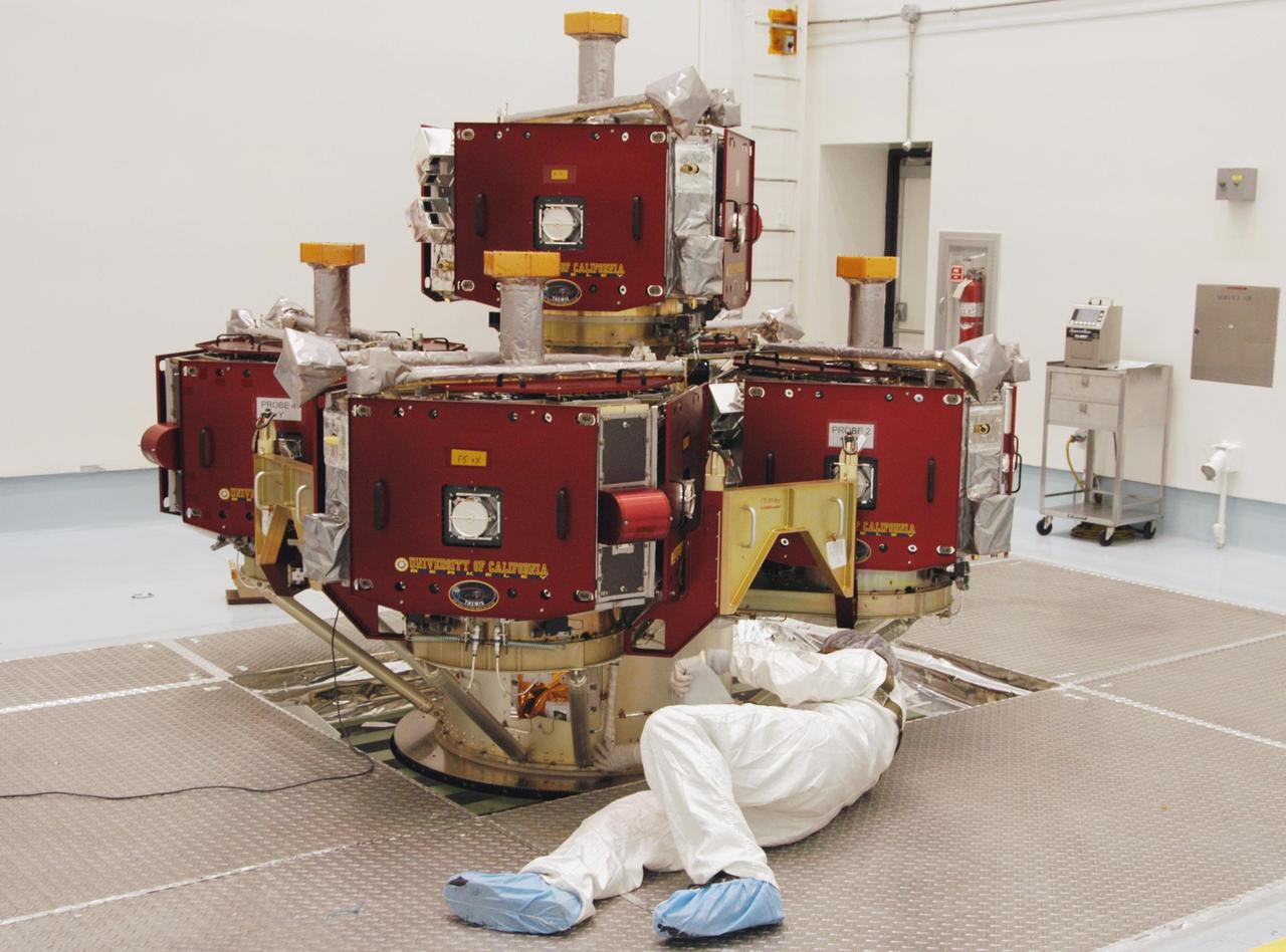 KENNEDY SPACE CENTER, FLA. -- In the Hazardous Processing Facility at Astrotech Space Operations, a worker checks data on the integrated THEMIS spacecraft sitting on the spin table. THEMIS consists of five identical probes, the largest number of scientific satellites ever launched into orbit aboard a single rocket. This unique constellation of satellites will resolve the tantalizing mystery of what causes the spectacular sudden brightening of the aurora borealis and aurora australis - the fiery skies over the Earth's northern and southern polar regions. THEMIS is scheduled to launch Feb. 15 from Cape Canaveral Air Force Station. Photo credit: NASA/George Shelton