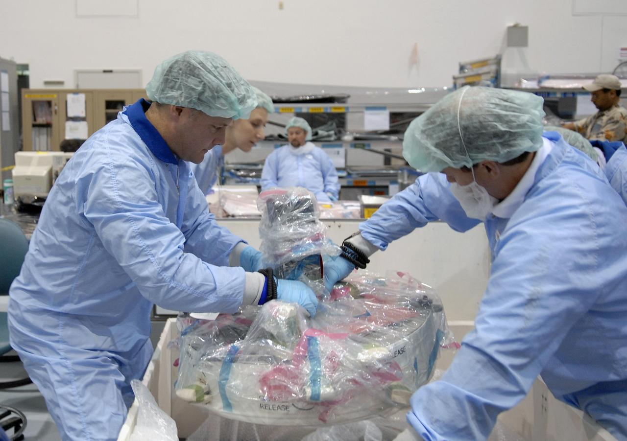 KENNEDY SPACE CENTER, FLA. --  STS-120 Mission Specialist Doug Wheelock (left) gets hands-on experience with equipment earmarked for the mission.  The primary payload for mission STS-120 is the U.S. Node 2, another element to be added to the International Space Station.  Node 2 will provide a passageway between three station science experiment facilities: the U.S. Destiny Laboratory, the Kibo Japanese Experiment Module, and the European Columbus Laboratory. STS-120 is targeted for launch on Sept. 7 with a crew of six, including Commander Pam Melroy, Pilot George Zamka, and Mission Specialist Mike Foreman.  Photo credit: NASA/Kim Shiflett