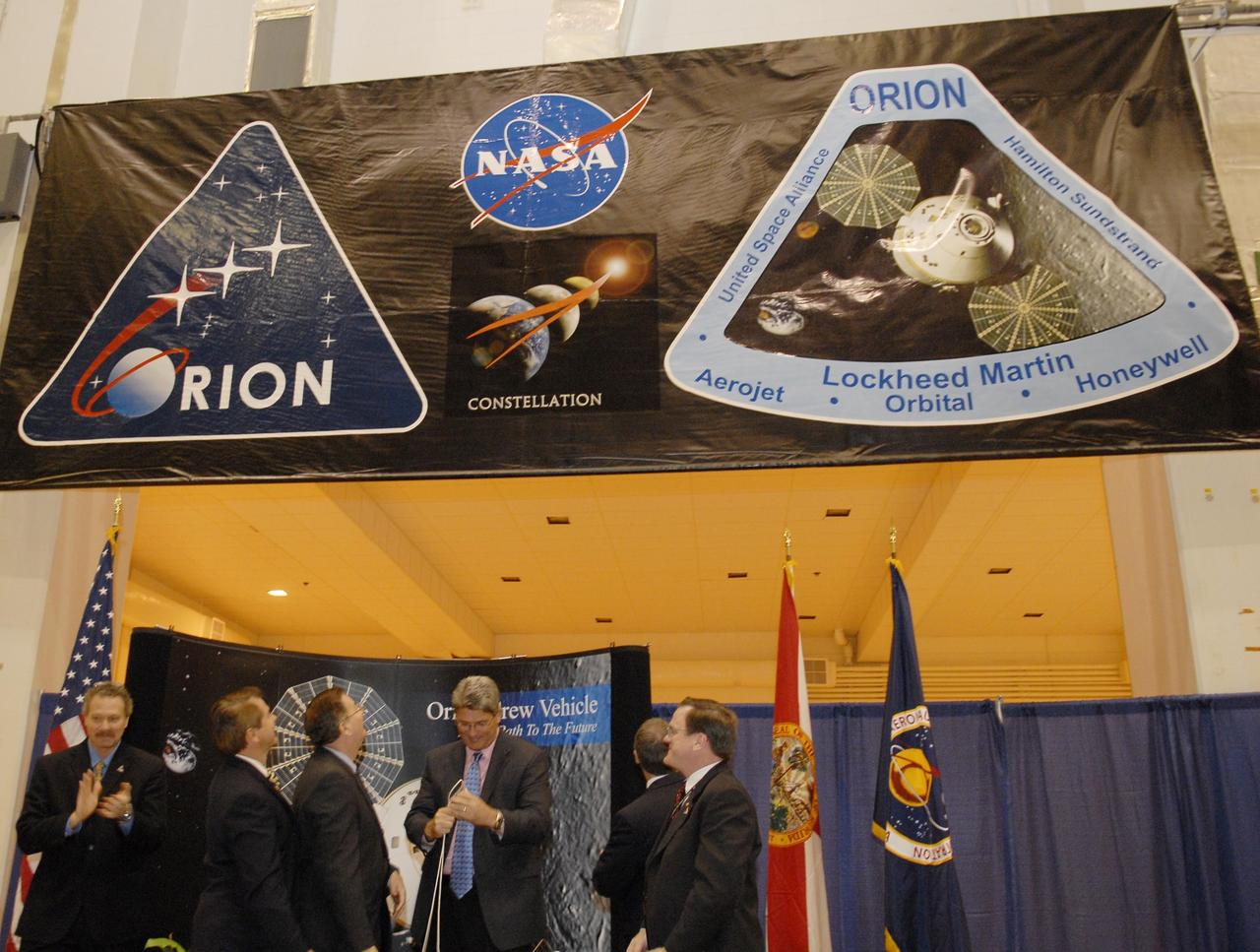 KENNEDY SPACE CENTER, FLA. -- After a ceremony to commemorate the transition of the historic Operations and Checkout (O&C) Building high bay for use by the Constellation Program, representatives from NASA, Lockheed Martin, Space Florida and the state of Florida look at the banner, unfurled by Kennedy Space Center Director Bill Parsons (center), spotlighting the Orion crew exploration vehicle that will be assembled in the O&C.  From left are Russell Romanella, director of the International Space Station/Payload Processing Directorate at Kennedy Space Center; Thad Altman, representative of the State of Florida; Cleon Lacefield, Lockheed Martin program manager; Parsons; Steve Koller, executive director of Space Florida (turned away); and Skip Hatfield, Orion Project manager.  Originally built to process space vehicles in the Apollo era, the O&C Building will serve as the final assembly facility for the Orion crew exploration vehicle. Orion, America's human spaceflight vehicle of the future, will be capable of transporting four crewmembers for lunar missions and later will support crew transfers for Mars missions. Each Orion spacecraft also may be used to support up to six crewmembers to the International Space Station after the space shuttle is retired in 2010.  Design, development and construction of Orion's components will be performed by Lockheed Martin for NASA at facilities throughout the country.  Photo credit: NASA/Kim Shiflett