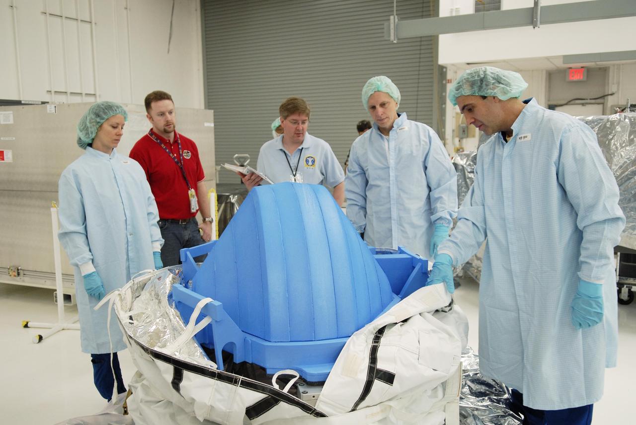 KENNEDY SPACE CENTER, FLA. -- In the Space Station Processing Facility, members of the STS-118 crew look at a mockup of the control moment gyro (CMG) and the insulating cover. The CMG is part of the payload on their mission. At the far left is Mission Specialist Tracy Caldwell; at right are Mission Specialists Clayton Anderson and Richard Mastracchio (holding the cover). Anderson will be flying on STS-118 to join the Expedition 15 crew as flight engineer on the International Space Station. The CMG will replace a faulty one on the International Space Station. The payload also includes the SPACEHAB single cargo module, the third starboard truss segment (ITS S5) and the external stowage platform 3 (ESP3). STS-118 is targeted to launch June 28 from Launch Pad 39A. Photo credit: NASA/Kim Shiflett