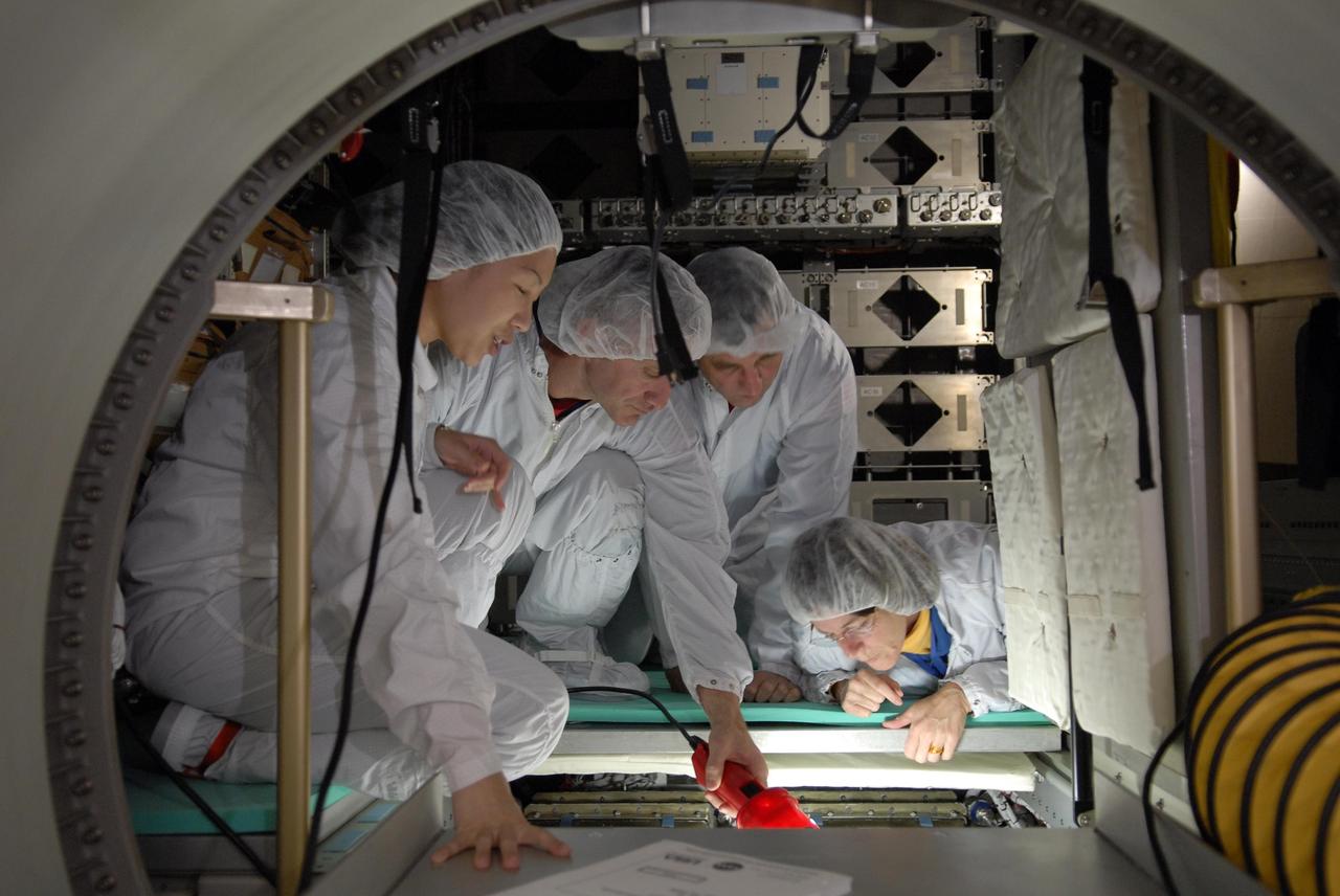 KENNEDY SPACE CENTER, FLA. -- Members of the STS-118 crew take part in a hardware review of the SPACEHAB module, part of the payload on their mission. Looking inside one of the stowage compartments are Pilot Charles Hobaugh (holding a light) and Mission Specialists Dafydd Williams and Barbara Morgan. Williams represents the Canadian Space Agency. The mission payload also includes the third starboard truss segment (ITS S5), a control moment gyro and the external stowage platform 3 (ESP3). STS-118 is targeted to launch June 28 from Launch Pad 39A. Photo credit: NASA/Kim Shiflett