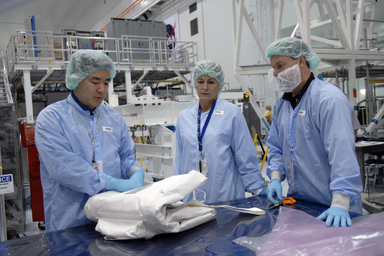 KENNEDY SPACE CENTER, FLA. -- On the floor of the Space Station Processing Facility, astronauts Dan Tani (left) and Peggy Whitson practice working with a cover, something they may handle during an upcoming shuttle flight.   With construction of the Space Station the primary focus of future shuttle missions, astronaut crews will be working with one or more of the elements and hardware already being processed in the SSPF.  Photo credit: NASA/Kim Shiflett