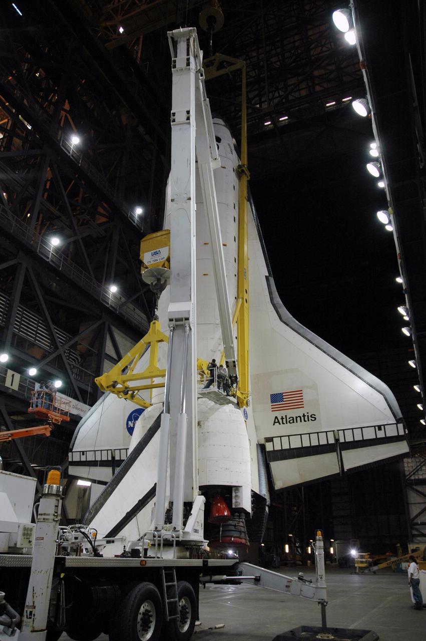 KENNEDY SPACE CENTER, FLA. --  In the transfer aisle of the Vehicle Assembly Building, workers adjust the sling attachment on the orbiter Atlantis.  The orbiter will be lifted up into high bay 1 and lowered onto the mobile launcher platform where the external tank and solid rocket boosters are already stacked.  Space Shuttle Atlantis is targeted to roll out to Launch Pad 39A on February 14 for mission STS-117. The mission is No. 21 to the International Space Station and construction flight 13A. Photo credit: NASA/Amanda Diller