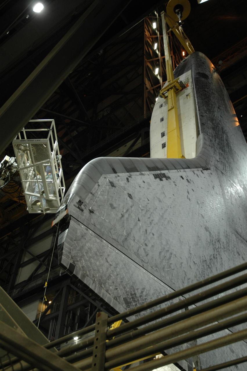 KENNEDY SPACE CENTER, FLA. --  In the transfer aisle of the Vehicle Assembly Building, workers take a close look at the orbiter Atlantis before it is lifted up into high bay 1.  After the lift, it will be lowered onto the mobile launcher platform where the external tank and solid rocket boosters are already stacked. Space Shuttle Atlantis is targeted to roll out to Launch Pad 39A on February 14 for mission STS-117. The mission is No. 21 to the International Space Station and construction flight 13A. Photo credit: NASA/Amanda Diller