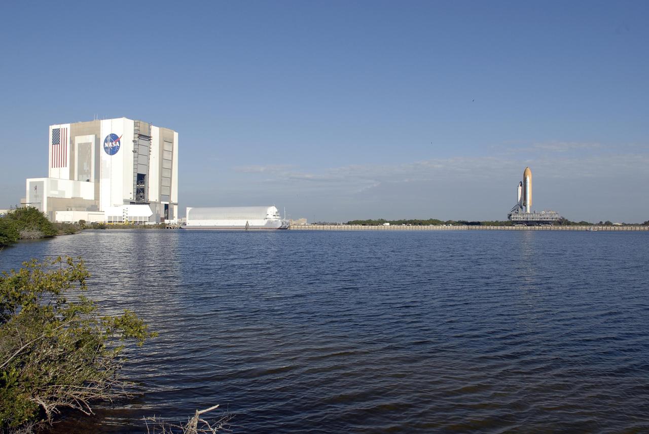 KENNEDY SPACE CENTER, FLA. -- Across the expanse of the turn basin, Space Shuttle Atlantis is seen as it creeps toward Launch Pad 39A. At left is the 525-foot-tall Vehicle Assembly Building. First motion was at 8:19 a.m. The 3.4-mile trip along the crawlerway will take about 6 hours. The mission payload aboard Space Shuttle Atlantis is the S3/S4 integrated truss structure, along with a third set of solar arrays and batteries. The crew of six astronauts will install the truss to continue assembly of the International Space Station. Launch is targeted for March 15. Photo credit: NASA/Kim Shiflett