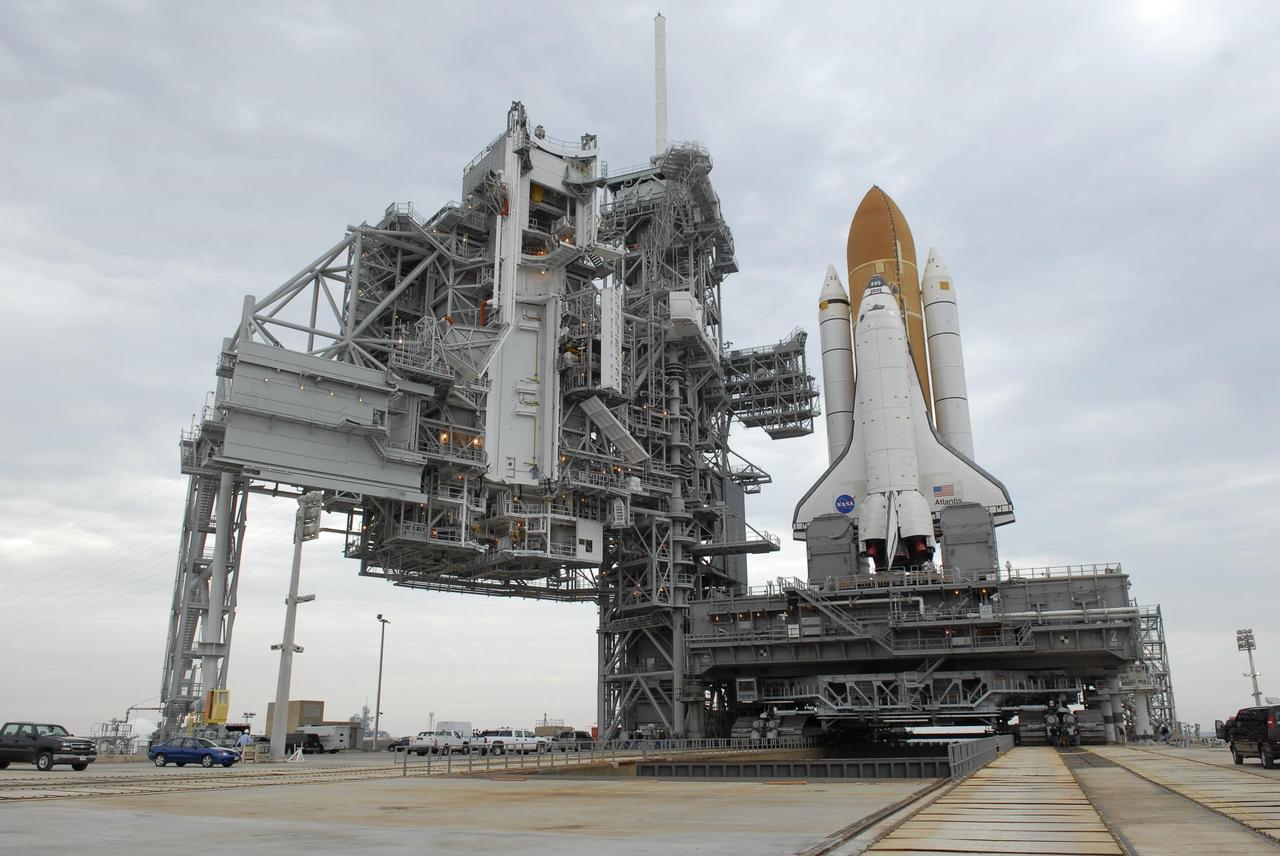 KENNEDY SPACE CENTER, FLA. -- Space Shuttle Atlantis arrives on the hardstand on Launch Pad 39A after a six-hour trek, via the crawler-transporter, from the Vehicle Assembly Building. The first motion out of the assembly building was at 8:19 a.m. At left is the open rotating service structure that will be rolled to enclose the shuttle for protection. Next to the shuttle is the fixed service structure. The mission payload aboard Space Shuttle Atlantis is the S3/S4 integrated truss structure, along with a third set of solar arrays and batteries. The crew of six astronauts will install the truss to continue assembly of the International Space Station. Launch is targeted for March 15. Photo credit: NASA/Kim Shiflett
