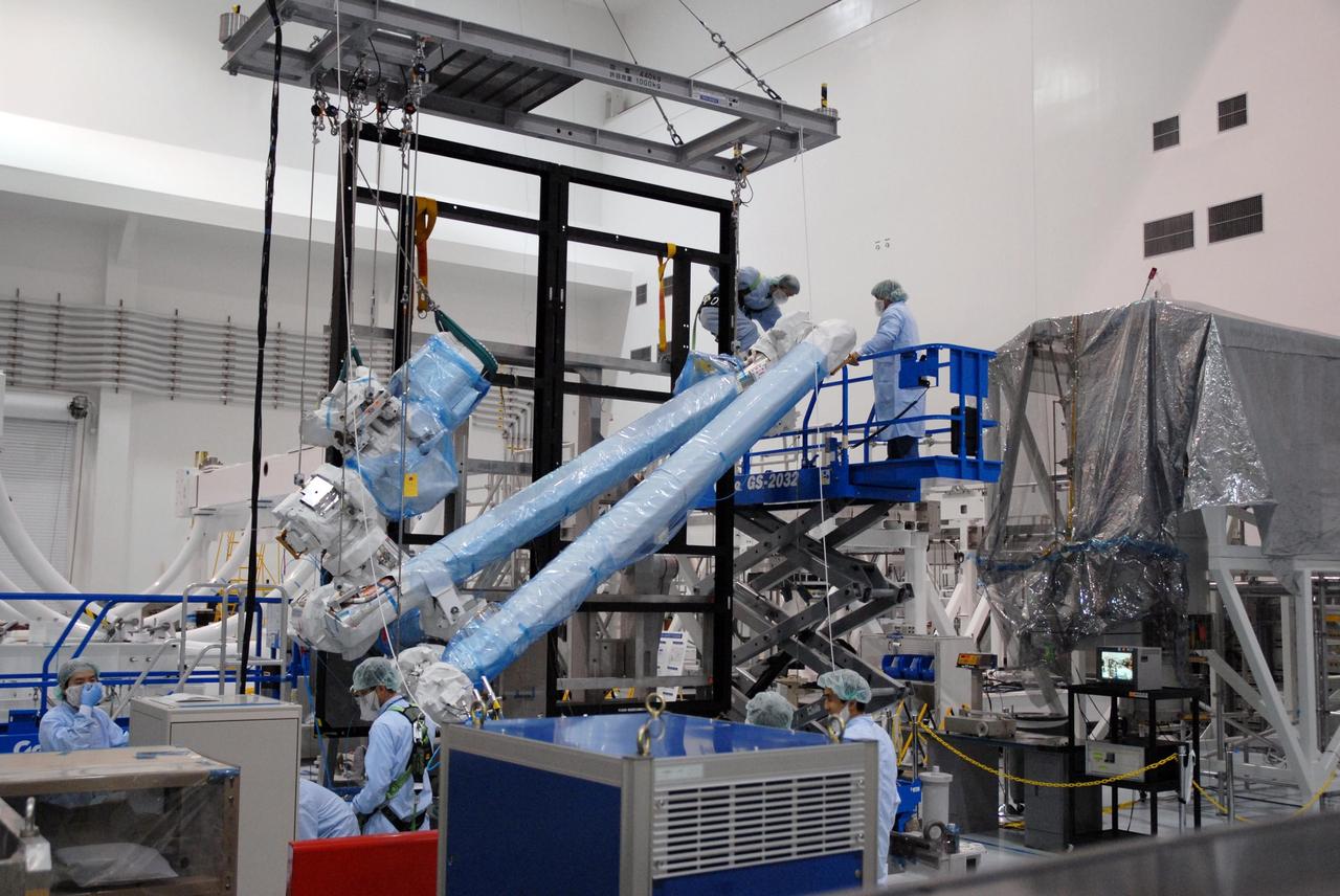 KENNEDY SPACE CENTER, FLA. -- Inside the Space Station Processing Facility at Kennedy Space Center, workers attach the Remote Manipulator System, or robotic arm, to a hoisting device to prepare for installation to the Japanese Experiment Module for testing. The RMS is one of the payloads scheduled to be delivered to the station on a future mission tentatively scheduled for 2008. The RMS is similar to the robotic arm already installed on the station's mobile base system. Photo credit: NASA/Amanda Diller