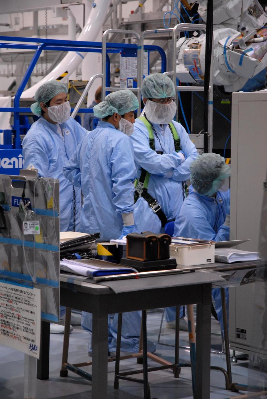 KENNEDY SPACE CENTER, FLA. -- Inside the Space Station Processing Facility at Kennedy Space Center, workers from the Japan Aerospace Exploration Agency watch from a control area as the Remote Manipulator System, or robotic arm, is attached to a hoisting device to prepare it for installation to the Japanese Experiment Module for testing. The RMS is one of the payloads scheduled to be delivered to the station on a future mission tentatively scheduled for 2008. The RMS is similar to the robotic arm already installed on the station's mobile base system.  Photo credit: NASA/Amanda Diller