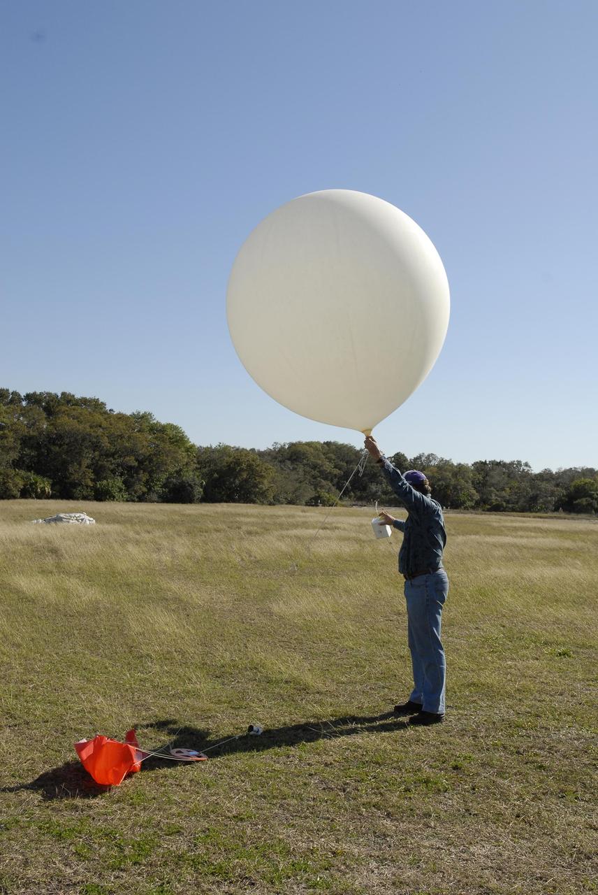 KENNEDY SPACE CENTER, FLA. -- A worker prepares to release a weather balloon outside the Cape Canaveral Air Force Station weather station. The balloon is equipped with a radiosonde, an instrument that transmits measurements on atmospheric pressure, humidity, temperature and winds as it ascends. The data will be used to determine if conditions are acceptable for the launch of NASA's THEMIS mission. THEMIS, an acronym for Time History of Events and Macroscale Interactions during Substorms, consists of five identical probes that will track violent, colorful eruptions near the North Pole.  This will be the largest number of scientific satellites NASA has ever launched into orbit aboard a single rocket.  The THEMIS mission aims to unravel the mystery behind auroral substorms, an avalanche of magnetic energy powered by the solar wind that intensifies the northern and southern lights.  The mission will investigate what causes auroras in the Earth’s atmosphere to dramatically change from slowly shimmering waves of light to wildly shifting streaks of bright color. Launch is planned from Pad 17-B in a window that extends from 6:01 to 6:19 p.m. EST.  Photo credit: NASA/Kim Shiflett