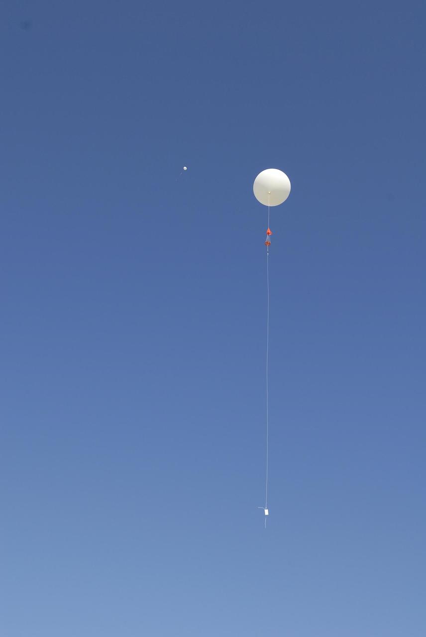 KENNEDY SPACE CENTER, FLA. -- Two weather balloons take flight from the Cape Canaveral Air Force Station weather station. Each balloon is equipped with a radiosonde, an instrument that transmits measurements on atmospheric pressure, humidity, temperature and winds as it ascends. The data will be used to determine if conditions are acceptable for the launch of NASA's THEMIS mission. THEMIS, an acronym for Time History of Events and Macroscale Interactions during Substorms, consists of five identical probes that will track violent, colorful eruptions near the North Pole.  This will be the largest number of scientific satellites NASA has ever launched into orbit aboard a single rocket.  The THEMIS mission aims to unravel the mystery behind auroral substorms, an avalanche of magnetic energy powered by the solar wind that intensifies the northern and southern lights.  The mission will investigate what causes auroras in the Earth’s atmosphere to dramatically change from slowly shimmering waves of light to wildly shifting streaks of bright color. Launch is planned from Pad 17-B in a window that extends from 6:01 to 6:19 p.m. EST.  Photo credit: NASA/Kim Shiflett