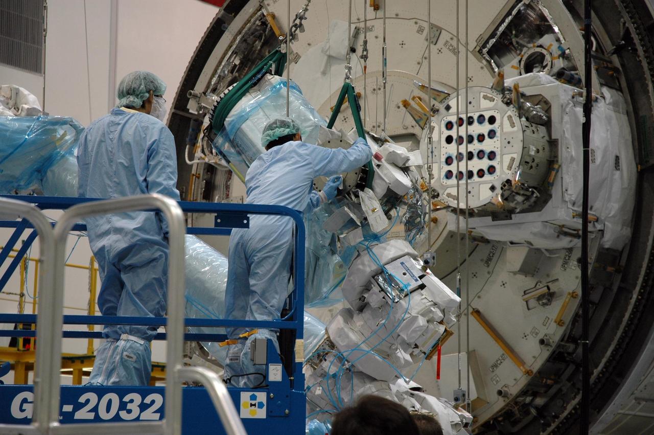 KENNEDY SPACE CENTER, FLA. -- Inside the Space Station Processing Facility at Kennedy Space Center, workers attach the Remote Manipulator System, or robotic arm, to the Japanese Experiment Module for testing. The RMS is one of the payloads scheduled to be delivered to the station on a future mission tentatively scheduled for 2008. The RMS is similar to the robotic arm already installed on the station's mobile base system. Photo credit: NASA/Amanda Diller
