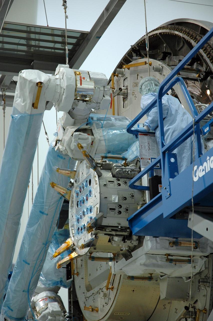 KENNEDY SPACE CENTER, FLA. -- Inside the Space Station Processing Facility at Kennedy Space Center, a worker helps to attach the Remote Manipulator System, or robotic arm, to the Japanese Experiment Module for testing. The RMS is one of the payloads scheduled to be delivered to the station on a future mission tentatively scheduled for 2008. The RMS is similar to the robotic arm already installed on the station's mobile base system. Photo credit: NASA/Amanda Diller