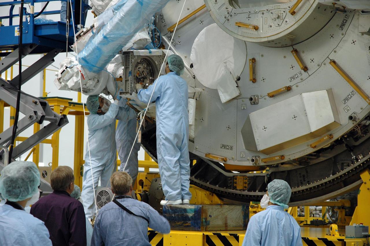 KENNEDY SPACE CENTER, FLA. -- Inside the Space Station Processing Facility at Kennedy Space Center, workers attach the Remote Manipulator System, or robotic arm, to the Japanese Experiment Module for testing. The RMS is one of the payloads scheduled to be delivered to the station on a future mission tentatively scheduled for 2008. The RMS is similar to the robotic arm already installed on the station's mobile base system. Photo credit: NASA/Amanda Diller
