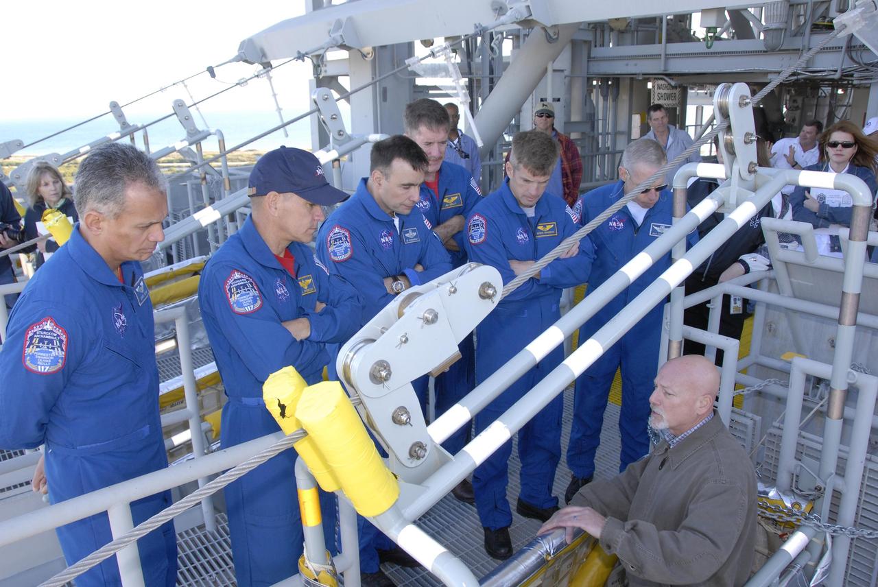 KENNEDY SPACE CENTER, FLA. --  At the 195-foot level of the fixed service structure on Launch Pad 39A, STS-117 crew members receive instruction on emergency egress during Terminal Countdown Demonstration Test activities. From left are Mission Specialist Danny Olivas, Commander Rick Sturckow, Pilot Lee Archambault, and Mission Specialists James Reilly, Steven Swanson and Patrick Forrester. They are practicing the emergency egress procedure using the slidewire basket system to get off the pad. The TCDT also includes M-113 armored personnel carrier training, and a simulated launch countdown. The mission payload aboard Space Shuttle Atlantis is the S3/S4 integrated truss structure, along with a third set of solar arrays and batteries. The crew of six astronauts will install the truss to continue assembly of the International Space Station. Photo credit: NASA/Kim Shiflett