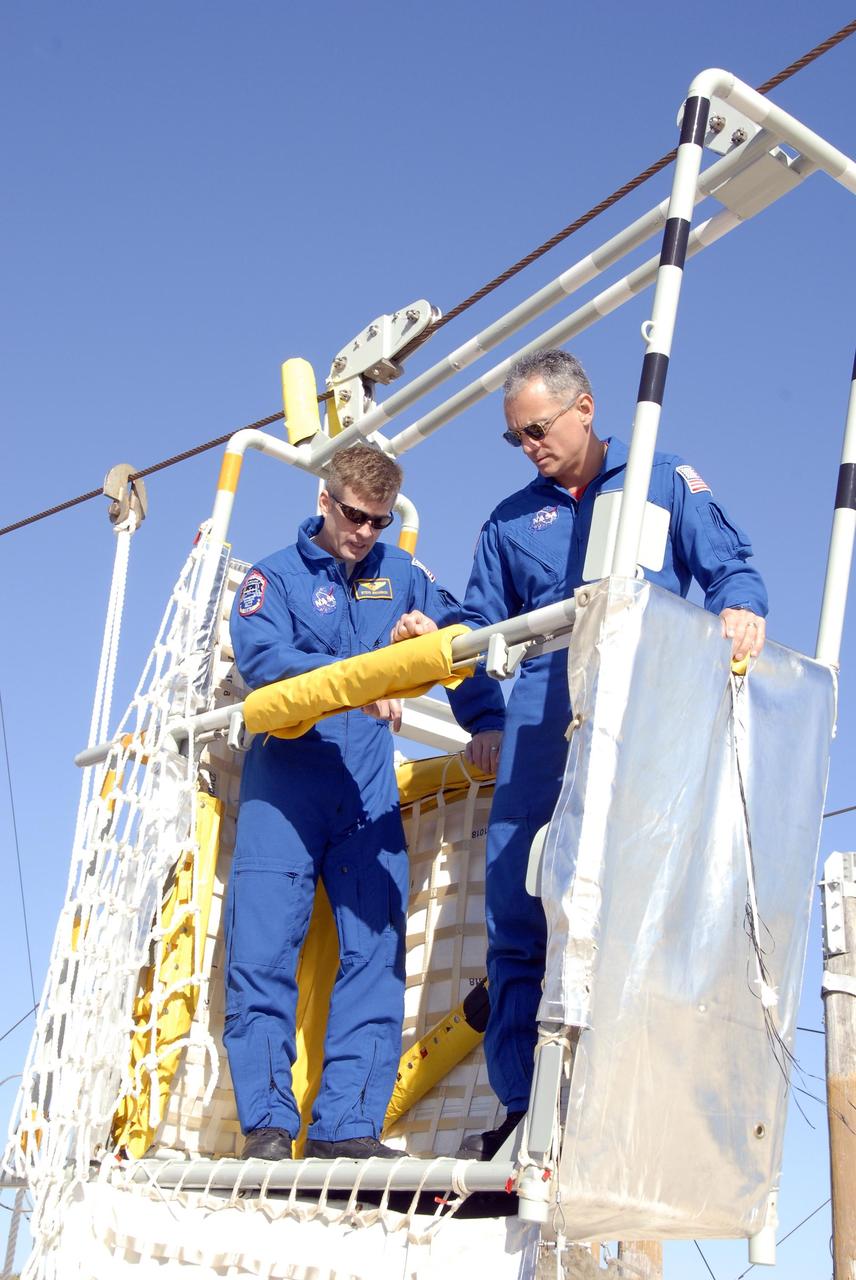 KENNEDY SPACE CENTER, FLA. --  In the Launch Pad 39A area, Mission STS-117 crew members receive instruction on emergency egress using the slidewire basket system during Terminal Countdown Demonstration Test activities. Here, Mission Specialists Steven Swanson (left) and Danny Olivas (right) practice exiting from the slidewire basket. The TCDT also includes M-113 armored personnel carrier training, and a simulated launch countdown. The mission payload aboard Space Shuttle Atlantis is the S3/S4 integrated truss structure, along with a third set of solar arrays and batteries. The crew of six astronauts will install the truss to continue assembly of the International Space Station. Photo credit: NASA/Kim Shiflett