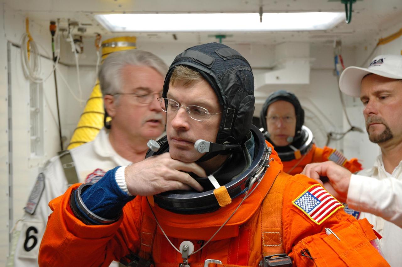 KENNEDY SPACE CENTER, FLA. -- In the white room on Launch Pad 39A, Mission STS-117 Mission Specialist Steven Swanson is helped with his gear before entering Space Shuttle Atlantis. The STS-117 crew practices for launch with a simulation of activities, from suit-up to countdown in the orbiter during terminal countdown demonstration test activities. The STS-117 mission is No. 21 to the International Space Station. Mission payloads aboard Atlantis include the S3/S4 integrated truss structure, a third set of solar arrays and batteries. The crew of six astronauts will install the truss to continue assembly of the station. Launch is scheduled for no earlier than March 15. Photo credit: NASA/Jim Grossmann