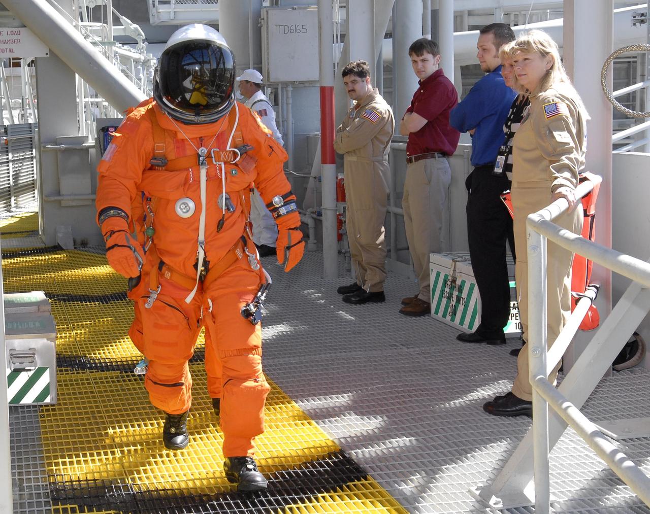KENNEDY SPACE CENTER, FLA. --   On the 195-foot level of the fixed service structure on Launch Pad 39A,  STS-117 Mission Specialists Steven Swanson and Patrick Forrester (directly behind him) head for the slidewire baskets. They and other crew members are practicing the emergency egress procedure to get off the pad, part of the prelaunch preparations known as terminal countdown demonstration test (TCDT). The TCDT also includes M-113 armored personnel carrier training and payload familiarization. The STS-117 mission is No. 21 to the International Space Station. Mission payloads aboard Atlantis include the S3/S4 integrated truss structure, a third set of solar arrays and batteries. The crew of six astronauts will install the truss to continue assembly of the station. Launch is scheduled for no earlier than March 15.   Photo credit: NASA/Kim Shiflett.