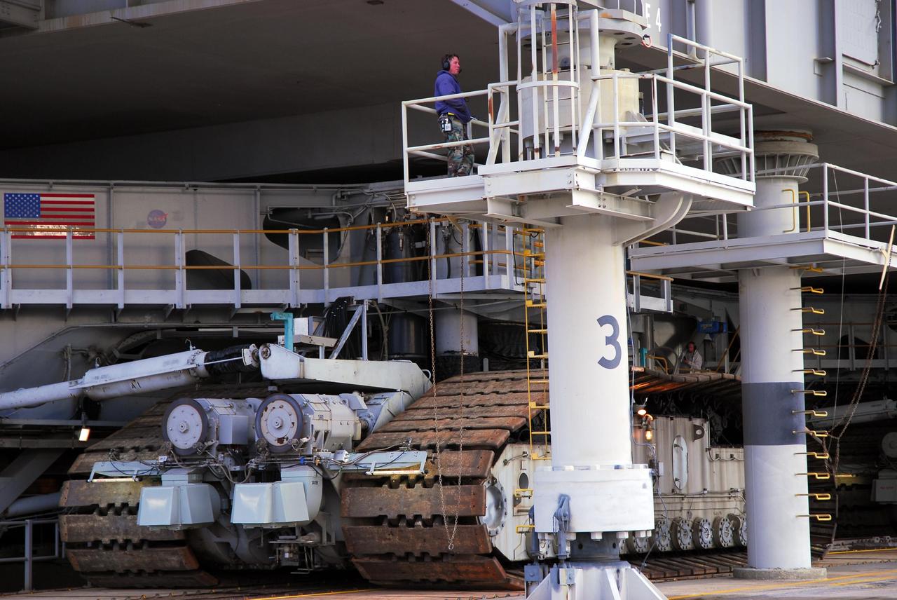 KENNEDY SPACE CENTER, FLA. --   The crawler-transporter, with its massive treads, has moved under the mobile launcher platform holding Space Shuttle Atlantis on Launch Pad 39A.  The crawler will move the shuttle back to the Vehicle Assembly Building where the shuttle will be examined for hail damage. A severe thunderstorm with golf ball-sized hail caused divots in the giant tank's foam insulation and minor surface damage to about 26 heat shield tiles on the shuttle's left wing. Further evaluation of the tank is necessary to get an accurate accounting of foam damage and determine the type of repair required and the time needed for that work.  A new target launch date has not been determined, but teams will focus on preparing Atlantis for liftoff in late April.  Photo credit: NASA/Amanda Diller