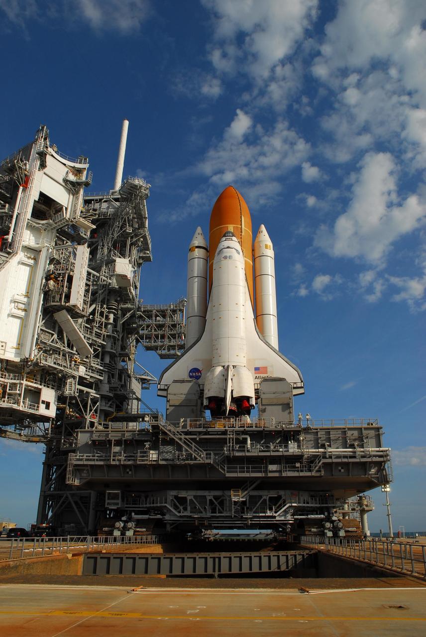 KENNEDY SPACE CENTER, FLA. --   In the early morning light on Launch Pad 39A, Space Shuttle Atlantis is revealed after rollback of the rotating service structure (at left).  The shuttle is being rolled back to the Vehicle Assembly Building where it will be examined for hail damage.  A severe thunderstorm with golf ball-sized hail caused divots in the giant tank's foam insulation and minor surface damage to about 26 heat shield tiles on the shuttle's left wing. Further evaluation of the tank is necessary to get an accurate accounting of foam damage and determine the type of repair required and the time needed for that work.  A new target launch date has not been determined, but teams will focus on preparing Atlantis for liftoff in late April.  Photo credit: NASA/Amanda Diller