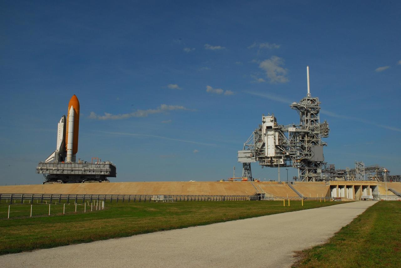KENNEDY SPACE CENTER, FLA. --  Under a nearly clear blue sky, Space Shuttle Atlantis (left) is being rolled back to the Vehicle Assembly Building from Launch Pad 39A.  In the VAB, the shuttle will be examined for hail damage.  A severe thunderstorm with golf ball-sized hail caused divots in the giant tank's foam insulation and minor surface damage to about 26 heat shield tiles on the shuttle's left wing. Further evaluation of the tank is necessary to get an accurate accounting of foam damage and determine the type of repair required and the time needed for that work.  A new target launch date has not been determined, but teams will focus on preparing Atlantis for liftoff in late April.  Photo credit: NASA/Amanda Diller