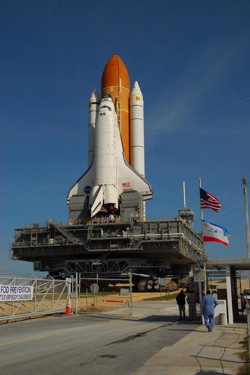 KENNEDY SPACE CENTER, FLA. --  Under a nearly clear blue sky, Space Shuttle Atlantis rolls through the gate to Launch Pad 39A on its way back to the Vehicle Assembly Building.  In the VAB, the shuttle will be examined for hail damage.  A severe thunderstorm with golf ball-sized hail caused divots in the giant tank's foam insulation and minor surface damage to about 26 heat shield tiles on the shuttle's left wing. Further evaluation of the tank is necessary to get an accurate accounting of foam damage and determine the type of repair required and the time needed for that work.  A new target launch date has not been determined, but teams will focus on preparing Atlantis for liftoff in late April.  Photo credit: NASA/Amanda Diller