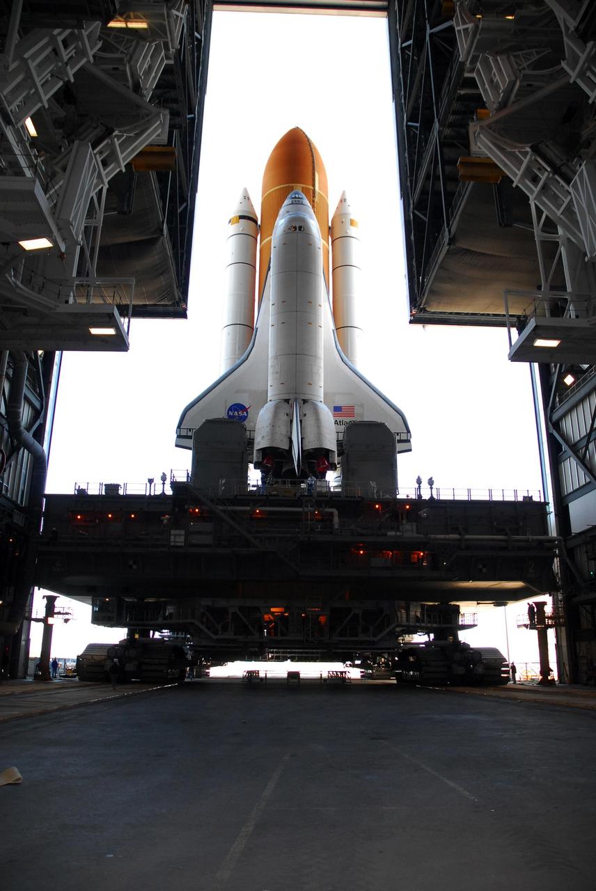 KENNEDY SPACE CENTER, FLA. --  Viewed from inside the Vehicle Assembly Building, Space Shuttle Atlantis, atop the mobile launcher platform, rolls through the door of high bay 1 after leaving Launch Pad 39A. In the VAB, the shuttle will be examined for hail damage. A severe thunderstorm with golf ball-sized hail caused divots in the giant tank's foam insulation and minor surface damage to about 26 heat shield tiles on the shuttle's left wing. Further evaluation of the tank is necessary to get an accurate accounting of foam damage and determine the type of repair required and the time needed for that work.  A new target launch date has not been determined, but teams will focus on preparing Atlantis for liftoff in late April.  Photo credit: NASA/Amanda Diller