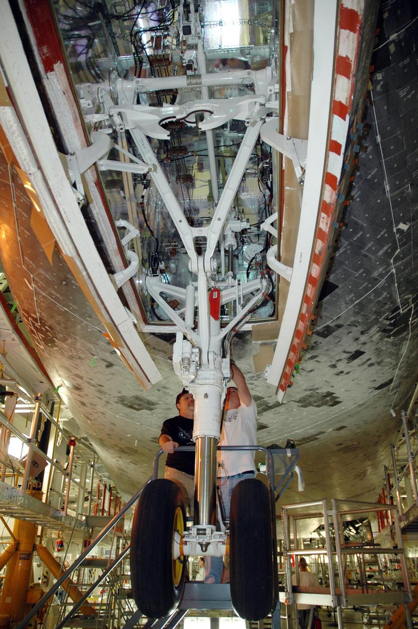 KENNEDY SPACE CENTER, FLA. --   In the Orbiter Processing Facility bay 2, technicians work around the attach point for the external tank near Endeavour's landing gear. The orbiter is scheduled to fly on mission STS-118 to the International Space Station in the summer of 2007.  Photo credit: NASA/Jack Pfaller