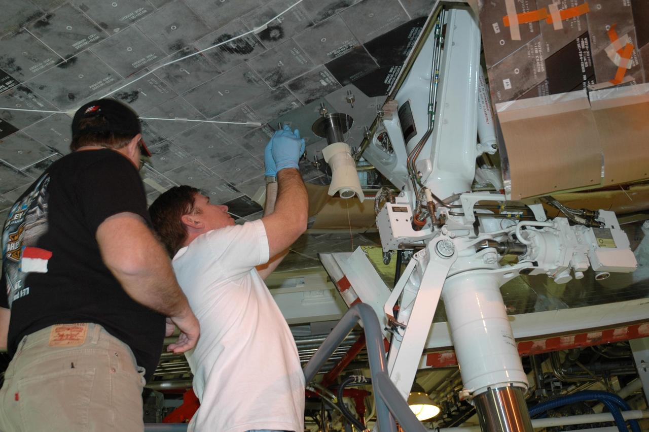 KENNEDY SPACE CENTER, FLA. --    In the Orbiter Processing Facility bay 2, technicians work around the attach point for the external tank near Endeavour's landing gear. The orbiter is scheduled to fly on mission STS-118 to the International Space Station in the summer of 2007.  Photo credit: NASA/Jack Pfaller