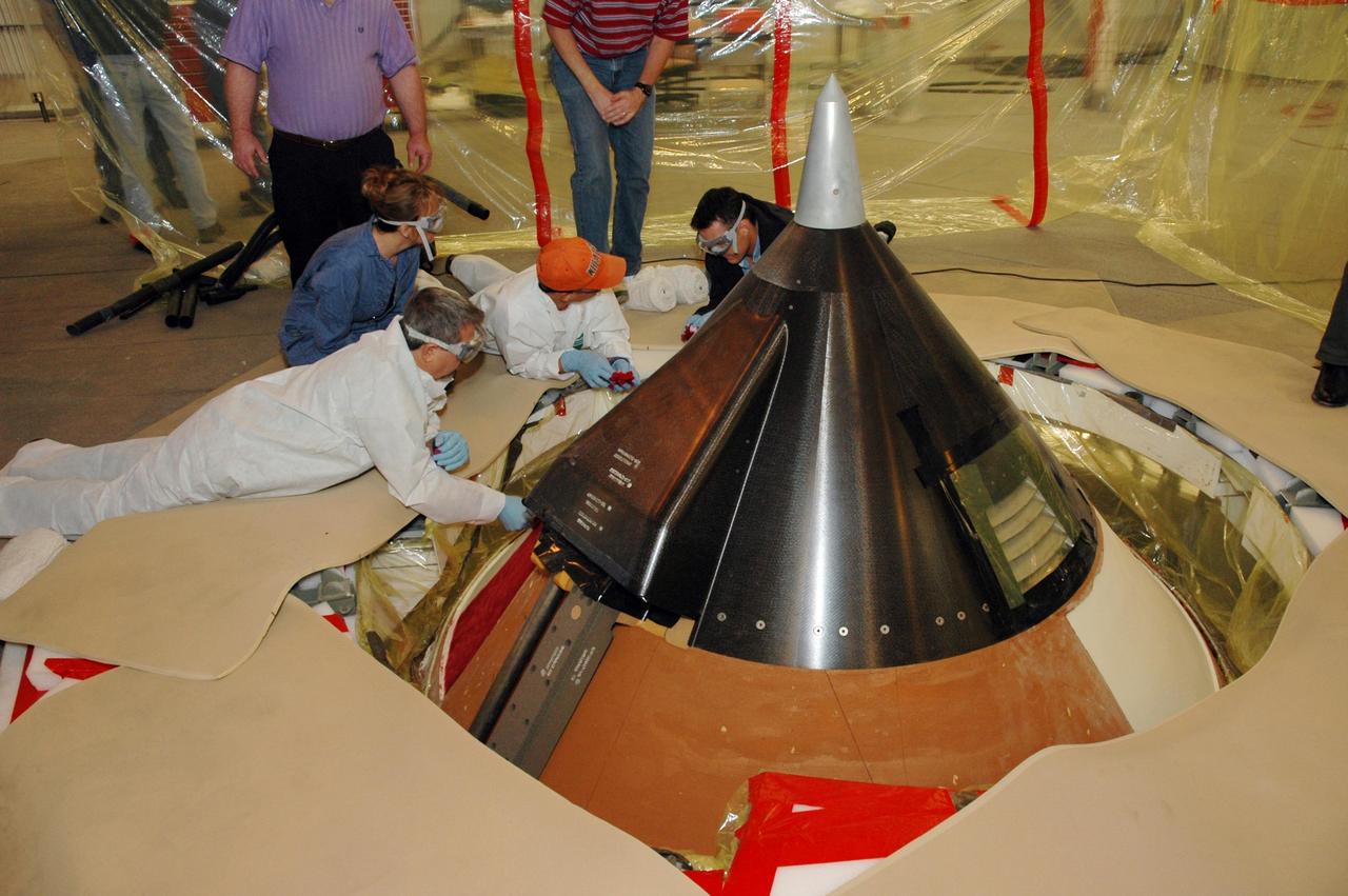 KENNEDY SPACE CENTER, FLA. -- In Highbay 1 inside the Vehicle Assembly Building, technicians perform repair techniques to the external tank inside a tented area that protects the top of the tank.  A severe thunderstorm with golf ball-sized hail caused visible divots in the giant tank's foam insulation and minor surface damage to about 26 heat shield tiles on the shuttle's left wing. A new target launch date has not been determined, but teams will focus on preparing Atlantis for liftoff in late April on mission STS-117. Photo credit: NASA/Jim Grossmann