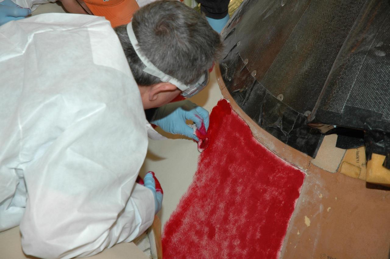 KENNEDY SPACE CENTER, FLA. -- In Highbay 1 inside the Vehicle Assembly Building, a technician carefully applies red dye to the external tank as part of repair operations. A severe thunderstorm with golf ball-sized hail caused visible divots in the giant tank's foam insulation and minor surface damage to about 26 heat shield tiles on the shuttle's left wing. A new target launch date has not been determined, but teams will focus on preparing Atlantis for liftoff in late April on mission STS-117. Photo credit: NASA/Jim Grossmann