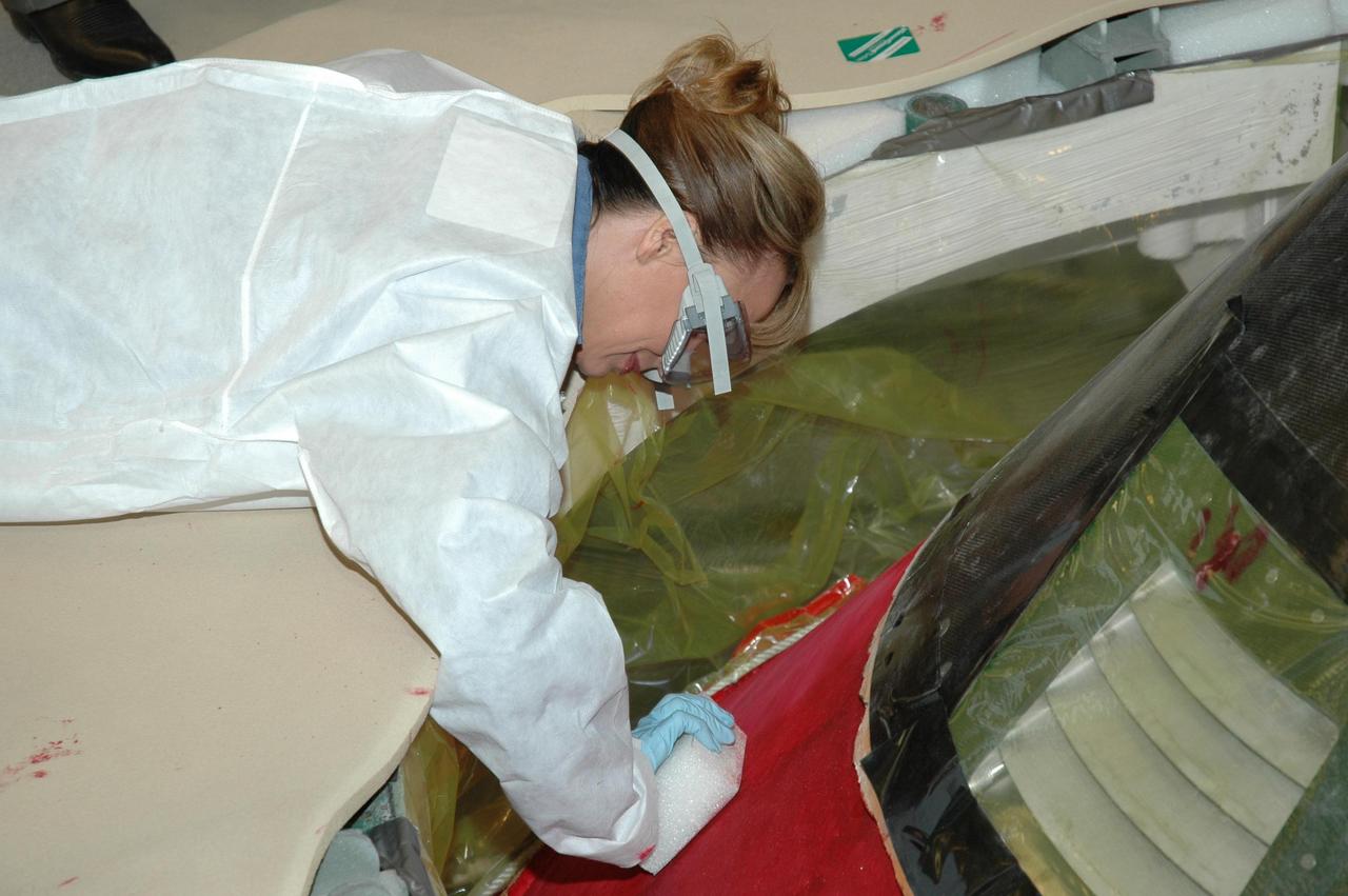 KENNEDY SPACE CENTER, FLA. -- In Highbay 1 inside the Vehicle Assembly Building, a technician carefully begins to sand away the red dye that has been applied to the external tank to help expose cracks or compression dents.  A severe thunderstorm with golf ball-sized hail caused visible divots in the giant tank's foam insulation and minor surface damage to about 26 heat shield tiles on the shuttle's left wing. A new target launch date has not been determined, but teams will focus on preparing Atlantis for liftoff in late April on mission STS-117. Photo credit: NASA/Jim Grossmann