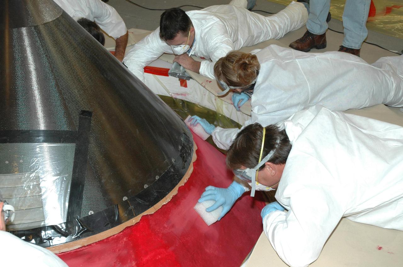 KENNEDY SPACE CENTER, FLA. -- In Highbay 1 inside the Vehicle Assembly Building, technicians begin to  carefully sand away the red dye that has been applied to the external tank to help expose cracks or compression dents.  A severe thunderstorm with golf ball-sized hail caused visible divots in the giant tank's foam insulation and minor surface damage to about 26 heat shield tiles on the shuttle's left wing. A new target launch date has not been determined, but teams will focus on preparing Atlantis for liftoff in late April on mission STS-117. Photo credit: NASA/Jim Grossmann