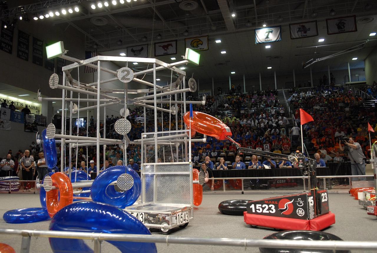 KENNEDY SPACE CENTER, FLA. --    Competing robots try to loop the large meta target with colored rings.  The robots are products of student teams taking part in the FIRST robotics event held at the University of Central Florida Arena March 8-10.  The FIRST, or For Inspiration and Recognition of Science and Technology, Robotics Competition challenges teams of young people and their mentors to solve a common problem in a six-week timeframe using a standard "kit of parts" and a common set of rules. Teams build robots from the parts and enter them in a series of competitions designed by FIRST founder Dean Kamen and Dr. Woodie Flowers, chairman and vice chairman of the Executive Advisory Board respectively, and a committee of engineers and other professionals. FIRST redefines winning for these students. Teams are rewarded for excellence in design, demonstrated team spirit, gracious professionalism and maturity, and ability to overcome obstacles. Scoring the most points is a secondary goal. Winning means building partnerships that last. Photo credit: NASA/Kim Shiflett