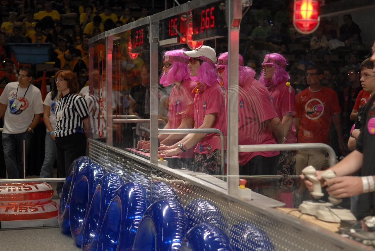 KENNEDY SPACE CENTER, FLA. --  The student team no. 233 dressed in pink controls its robot during competition in the FIRST robotics event held at the University of Central Florida Arena March 8-10.  The team is a coordinated effort co-sponsored by NASA KSC and representing Rockledge, Cocoa Beach and Viera High Schools in Central Florida.  The FIRST, or For Inspiration and Recognition of Science and Technology, Robotics Competition challenges teams of young people and their mentors to solve a common problem in a six-week timeframe using a standard "kit of parts" and a common set of rules. Teams build robots from the parts and enter them in a series of competitions designed by FIRST founder Dean Kamen and Dr. Woodie Flowers, chairman and vice chairman of the Executive Advisory Board respectively, and a committee of engineers and other professionals. FIRST redefines winning for these students. Teams are rewarded for excellence in design, demonstrated team spirit, gracious professionalism and maturity, and ability to overcome obstacles. Scoring the most points is a secondary goal. Winning means building partnerships that last. Photo credit: NASA/Kim Shiflett