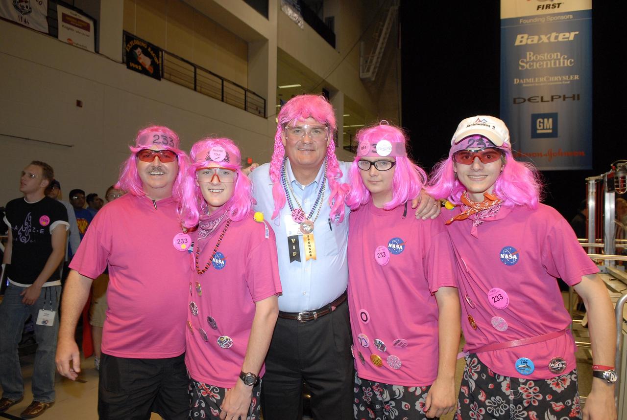 KENNEDY SPACE CENTER, FLA. --   During the FIRST robotics event held at the University of Central Florida Arena March 8-10, Center Director Bill Parsons (center) dons the pink wig that represents team no. 233, composed of students from Rockledge, Cocoa Beach and Viera High Schools in Central Florida.  The team is cosponsored by NASA KSC. The FIRST, or For Inspiration and Recognition of Science and Technology, Robotics Competition challenges teams of young people and their mentors to solve a common problem in a six-week timeframe using a standard "kit of parts" and a common set of rules. Teams build robots from the parts and enter them in a series of competitions designed by FIRST founder Dean Kamen and Dr. Woodie Flowers, chairman and vice chairman of the Executive Advisory Board respectively, and a committee of engineers and other professionals. FIRST redefines winning for these students. Teams are rewarded for excellence in design, demonstrated team spirit, gracious professionalism and maturity, and ability to overcome obstacles. Scoring the most points is a secondary goal. Winning means building partnerships that last. Photo credit: NASA/Kim Shiflett