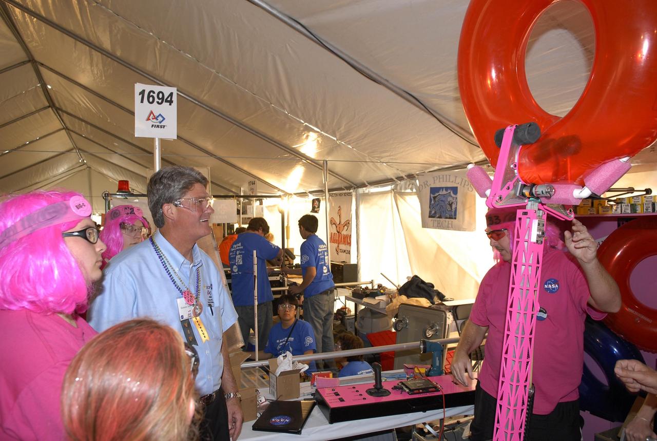KENNEDY SPACE CENTER, FLA. --   During the FIRST robotics event held at the University of Central Florida Arena March 8-10, Center Director Bill Parsons talks to the NASA-sponsored team, known as the Pink Team, from Rockledge, Cocoa Beach and Viera High Schools in Central Florida.  The FIRST, or For Inspiration and Recognition of Science and Technology, Robotics Competition challenges teams of young people and their mentors to solve a common problem in a six-week timeframe using a standard "kit of parts" and a common set of rules. Teams build robots from the parts and enter them in a series of competitions designed by FIRST founder Dean Kamen and Dr. Woodie Flowers, chairman and vice chairman of the Executive Advisory Board respectively, and a committee of engineers and other professionals. FIRST redefines winning for these students. Teams are rewarded for excellence in design, demonstrated team spirit, gracious professionalism and maturity, and ability to overcome obstacles. Scoring the most points is a secondary goal. Winning means building partnerships that last. Photo credit: NASA/Kim Shiflett