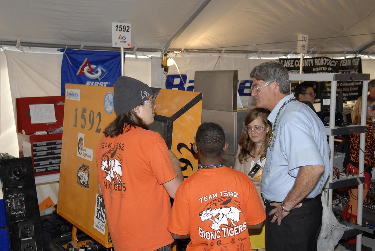 KENNEDY SPACE CENTER, FLA. --    Center Director Bill Parsons (right) talks with students of another NASA-sponsored robotic team during the FIRST robotics event held at the University of Central Florida Arena March 8-10. Next to Parsons is Lisa Malone, director of External Relations at Kennedy Space Center.  The students of team 1592, the Bionic Tigers, represent the cosponsors Analex Corporation and NASA Launch Services Program and Cocoa High School in Central Florida. Participating since 2005, this is the first year for this team to receive NASA financial support.  They were mentored by the Pink Team.  The FIRST, or For Inspiration and Recognition of Science and Technology, Robotics Competition challenges teams of young people and their mentors to solve a common problem in a six-week timeframe using a standard "kit of parts" and a common set of rules. Teams build robots from the parts and enter them in a series of competitions designed by FIRST founder Dean Kamen and Dr. Woodie Flowers, chairman and vice chairman of the Executive Advisory Board respectively, and a committee of engineers and other professionals. FIRST redefines winning for these students. Teams are rewarded for excellence in design, demonstrated team spirit, gracious professionalism and maturity, and ability to overcome obstacles. Scoring the most points is a secondary goal. Winning means building partnerships that last. Photo credit: NASA/Kim Shiflett