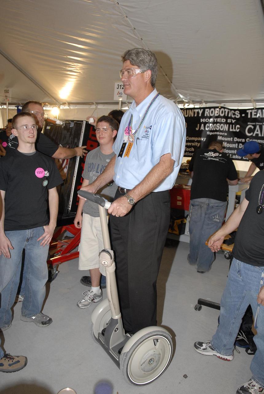 KENNEDY SPACE CENTER, FLA. --    During the FIRST robotics event held at the University of Central Florida Arena March 8-10, Center Director Bill Parsons takes a turn on the Segway® Personal Transporter (PT), designed by FIRST founder Dean Kamen. The FIRST, or For Inspiration and Recognition of Science and Technology, Robotics Competition challenges teams of young people and their mentors to solve a common problem in a six-week timeframe using a standard "kit of parts" and a common set of rules. Teams build robots from the parts and enter them in a series of competitions designed by FIRST founder Dean Kamen and Dr. Woodie Flowers, chairman and vice chairman of the Executive Advisory Board respectively, and a committee of engineers and other professionals. FIRST redefines winning for these students. Teams are rewarded for excellence in design, demonstrated team spirit, gracious professionalism and maturity, and ability to overcome obstacles. Scoring the most points is a secondary goal. Winning means building partnerships that last. Photo credit: NASA/Kim Shiflett