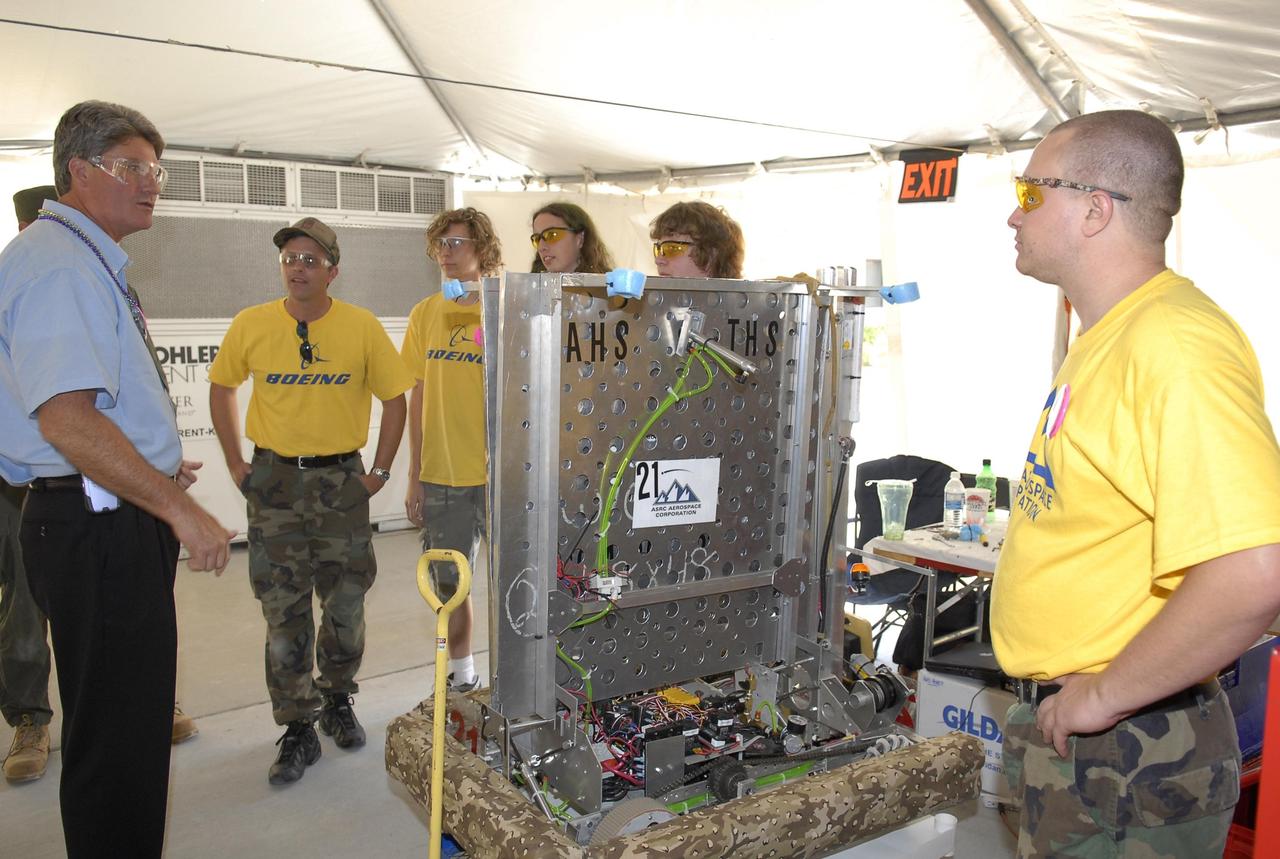 KENNEDY SPACE CENTER, FLA. --     During the FIRST robotics event held at the University of Central Florida Arena March 8-10, Center Director Bill Parsons (left) talks to students from Titusville, Fla., about their robot. The team is cosponsored by ASRC Aerospace and The Boeing Company, and represents Astronaut and Titusville High Schools.  The FIRST, or For Inspiration and Recognition of Science and Technology, Robotics Competition challenges teams of young people and their mentors to solve a common problem in a six-week timeframe using a standard "kit of parts" and a common set of rules. Teams build robots from the parts and enter them in a series of competitions designed by FIRST founder Dean Kamen and Dr. Woodie Flowers, chairman and vice chairman of the Executive Advisory Board respectively, and a committee of engineers and other professionals. FIRST redefines winning for these students. Teams are rewarded for excellence in design, demonstrated team spirit, gracious professionalism and maturity, and ability to overcome obstacles. Scoring the most points is a secondary goal. Winning means building partnerships that last. Photo credit: NASA/Kim Shiflett