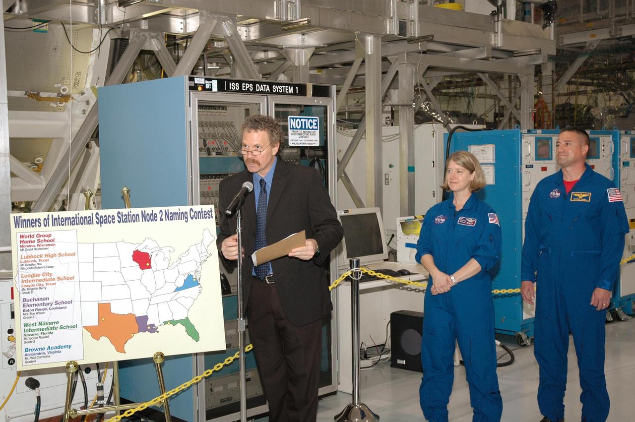 KENNEDY SPACE CENTER, FLA. -- In the Space Station Processing Facility, Russ Romanella (left), director of International Space Station and Spacecraft Processing, presides over a ceremony to unveil the new name of NASA's Node 2 module, Harmony. With him are Mission STS-120 Commander Pam Melroy and Pilot George Zamka. The name, Harmony, was chosen from an academic competition involving thousands of students in kindergarten through high school. The Node 2 Challenge required students to learn about the International Space Station, build a scale model of the module, and write an essay explaining their proposed name. This will be the first U.S. piece of the space station named by someone other than a NASA official. Node 2 is a pressurized module that will act as a connecting port and passageway to additional international science labs and supply spacecraft. It also will be a work platform for the station's robotic arm. The module is scheduled to fly on mission STS-120 aboard Space Shuttle Atlantis targeted for later this year. Photo credit: NASA/Jim Grossmann