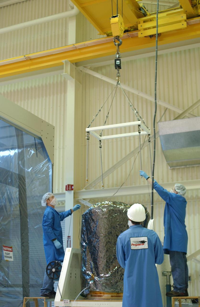 VANDENBERG AIR FORCE BASE, CALIF.  --   In Building 1555 at North Vandenberg Air Force Base, workers get ready to attach the overhead crane to the AIM spacecraft.  AIM will be moved into an area where a partial deployment of the solar arrays on the spacecraft will take place.  The AIM spacecraft will fly three instruments designed to study polar mesospheric clouds located at the edge of space, 50 miles above the Earth's surface in the coldest part of the planet's atmosphere. The mission's primary goal is to explain why these clouds form and what has caused them to become brighter and more numerous and appear at lower latitudes in recent years. AIM's results will provide the basis for the study of long-term variability in the mesospheric climate and its relationship to global climate change. AIM is scheduled to be mated to the Pegasus XL during the second week of April, after which final inspections will be conducted.  Launch is scheduled for April 25.