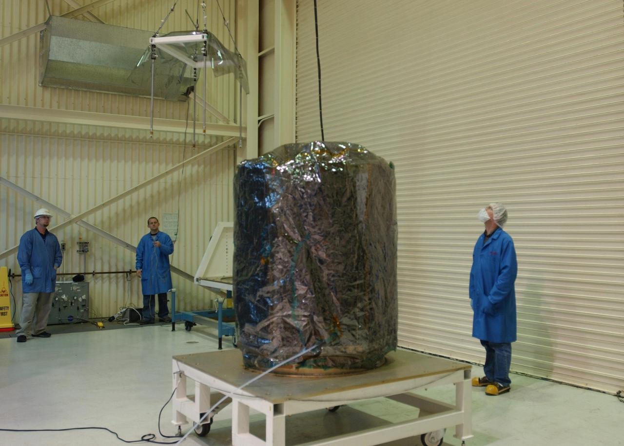 VANDENBERG AIR FORCE BASE, CALIF.  --  In Building 1555 at North Vandenberg Air Force Base, workers lower the AIM spacecraft onto a moveable base.  AIM will be moved into an area where a partial deployment of the solar arrays on the spacecraft will take place.The AIM spacecraft will fly three instruments designed to study polar mesospheric clouds located at the edge of space, 50 miles above the Earth's surface in the coldest part of the planet's atmosphere. The mission's primary goal is to explain why these clouds form and what has caused them to become brighter and more numerous and appear at lower latitudes in recent years. AIM's results will provide the basis for the study of long-term variability in the mesospheric climate and its relationship to global climate change. AIM is scheduled to be mated to the Pegasus XL during the second week of April, after which final inspections will be conducted.  Launch is scheduled for April 25.