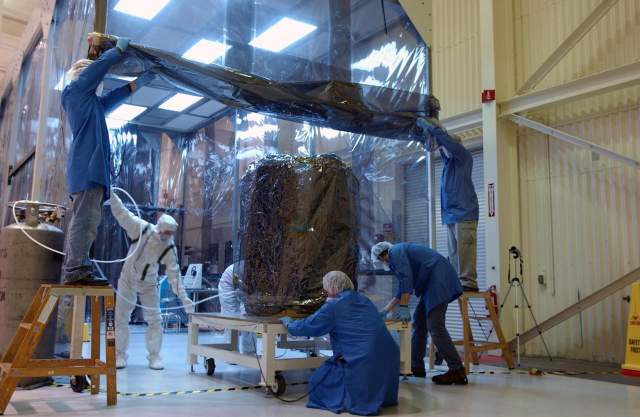 VANDENBERG AIR FORCE BASE, CALIF.  -- In Building 1555 at North Vandenberg Air Force Base, workers roll the AIM spacecraft into the "tent" where a partial deployment of the solar arrays on the spacecraft will take place. The AIM spacecraft will fly three instruments designed to study polar mesospheric clouds located at the edge of space, 50 miles above the Earth's surface in the coldest part of the planet's atmosphere. The mission's primary goal is to explain why these clouds form and what has caused them to become brighter and more numerous and appear at lower latitudes in recent years. AIM's results will provide the basis for the study of long-term variability in the mesospheric climate and its relationship to global climate change. AIM is scheduled to be mated to the Pegasus XL during the second week of April, after which final inspections will be conducted.  Launch is scheduled for April 25.