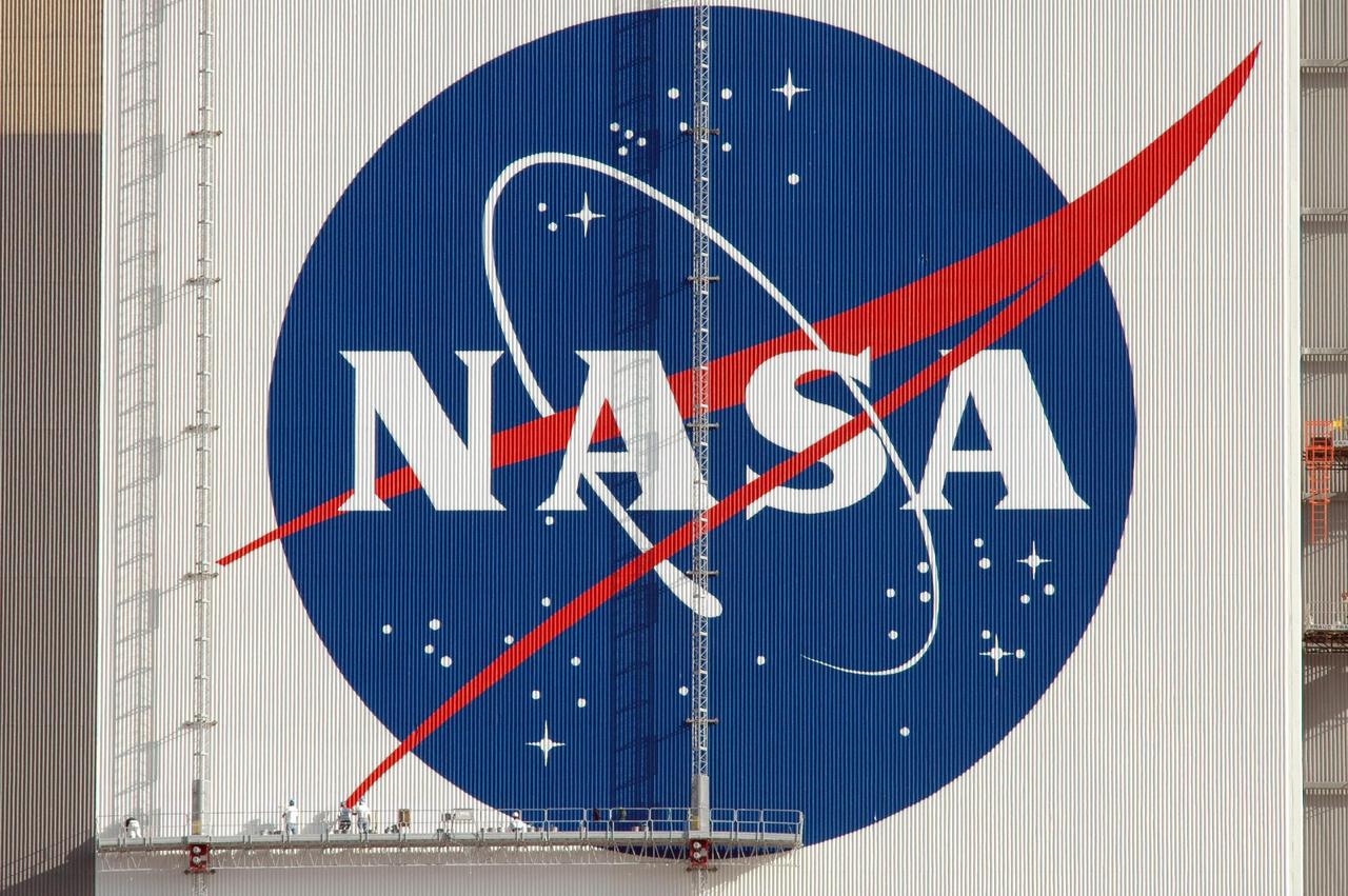 KENNEDY SPACE CENTER, FLA.  --   The NASA logo shines in the morning sun on the side of the Vehicle Assembly Building after completion of its repainting.  The logo, which is known as the "meatball," measures 110 feet by 132 feet, or about 12,300 square feet. The American flag was also painted on the side of the VAB.  The flag spans an area 209 feet by 110 feet, or about 23, 437 square feet. Each stripe is 9 feet wide and each star is 6 feet in diameter.  The flag and logo were last painted in 1998, honoring NASA's 40th anniversary.  Photo credit: NASA/Jim Grossmann