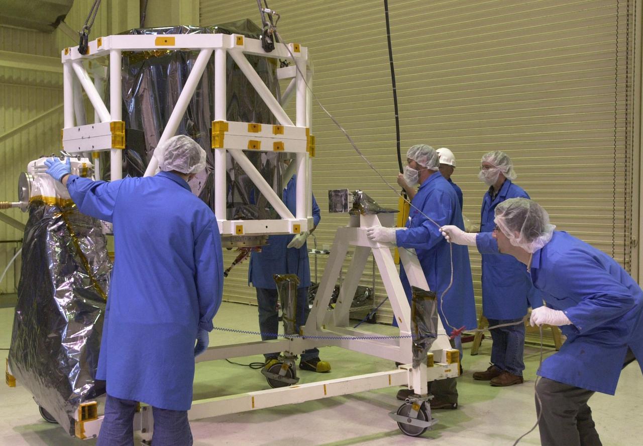 KENNEDY SPACE CENTER, FLA.  --   In Building 1555 on North Vandenberg Air Force Base in California, technicians lower the AIM spacecraft onto a moveable stand. AIM, which stands for Aeronomy of Ice in the Mesosphere, is being prepared for integrated testing and a flight simulation.  The AIM spacecraft will fly three instruments designed to study polar mesospheric clouds located at the edge of space, 50 miles above the Earth's surface in the coldest part of the planet's atmosphere. The mission's primary goal is to explain why these clouds form and what has caused them to become brighter and more numerous and appear at lower latitudes in recent years. AIM's results will provide the basis for the study of long-term variability in the mesospheric climate and its relationship to global climate change. AIM is scheduled to be mated to its launch vehicle, Orbital Sciences' Pegasus XL, during the second week of April, after which final inspections will be conducted.  Launch is scheduled for April 25.