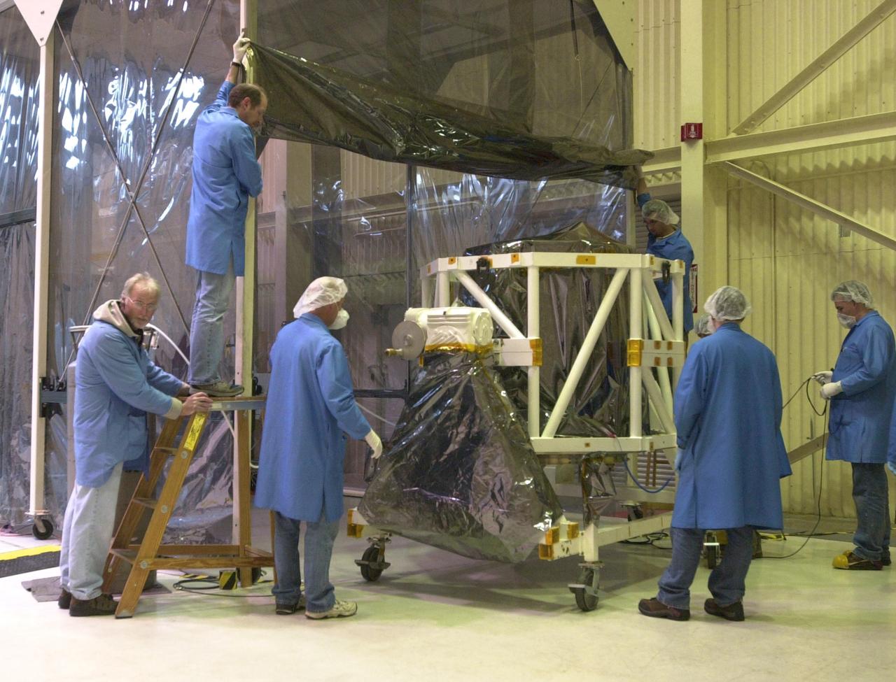 KENNEDY SPACE CENTER, FLA.  --    In Building 1555 on North Vandenberg Air Force Base in California, technicians roll the AIM spacecraft back under the protective clean tent. AIM, which stands for Aeronomy of Ice in the Mesosphere, is being prepared for integrated testing and a flight simulation.  The AIM spacecraft will fly three instruments designed to study polar mesospheric clouds located at the edge of space, 50 miles above the Earth's surface in the coldest part of the planet's atmosphere. The mission's primary goal is to explain why these clouds form and what has caused them to become brighter and more numerous and appear at lower latitudes in recent years. AIM's results will provide the basis for the study of long-term variability in the mesospheric climate and its relationship to global climate change. AIM is scheduled to be mated to its launch vehicle, Orbital Sciences' Pegasus XL, during the second week of April, after which final inspections will be conducted.  Launch is scheduled for April 25.