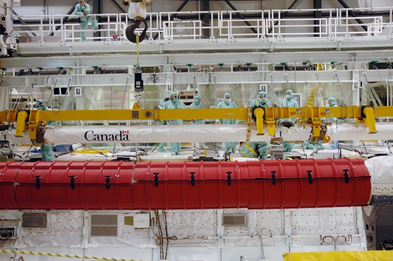 KENNEDY SPACE CENTER, FLA. -- In Orbiter Processing Facility bay 2, the orbiter boom sensor system (in the background) is lowered into the open payload bay of Endeavour. The boom will be installed in the payload bay for launch. The orbiter is scheduled to fly on mission STS-118 to the International Space Station in the summer of 2007. It will deliver the third starboard truss segment, S5. Photo credit: NASA/Troy Cryder